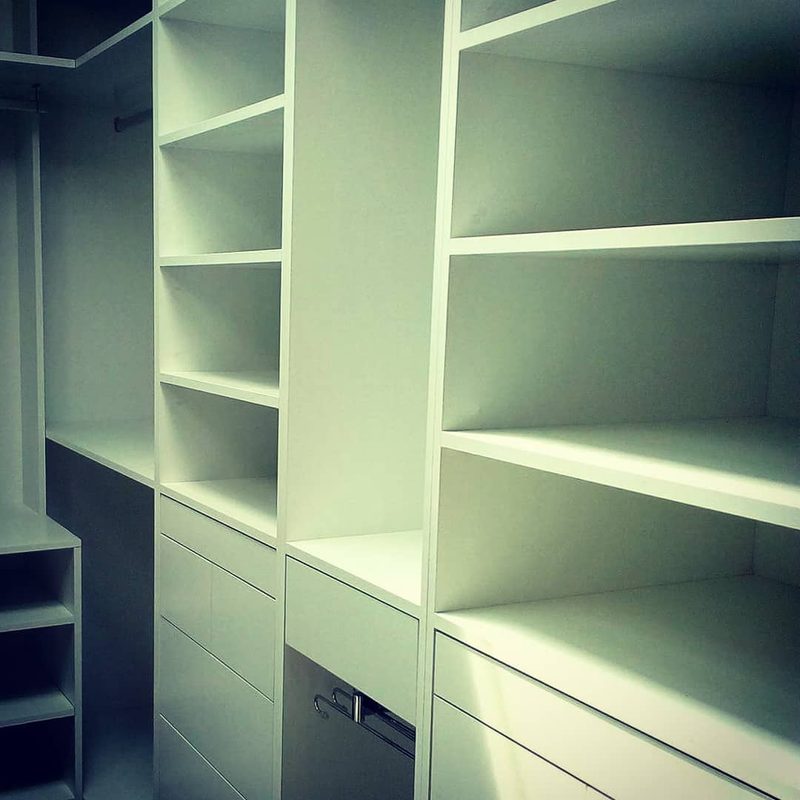 Interior de closet branco com prateleiras, gavetas e calceiro extraível