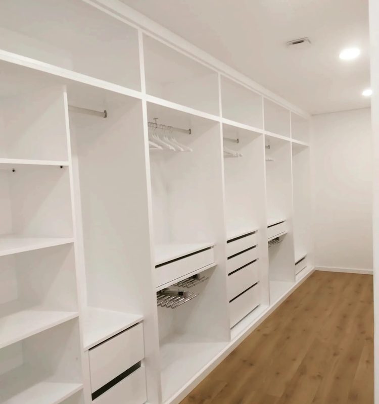 Closet branco por medida ao longo da parede, com prateleiras, gavetas e varões