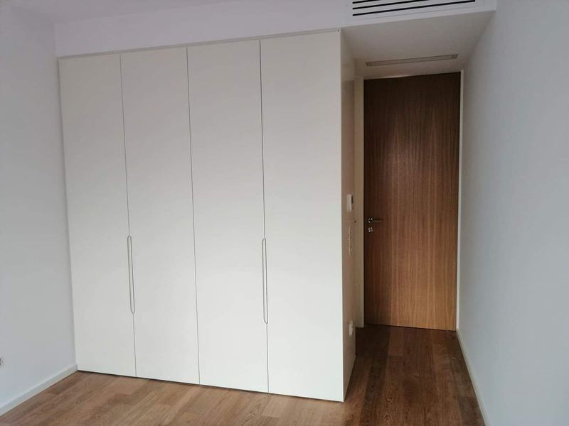 Roupeiro embutido branco ao lado de porta interior em madeira